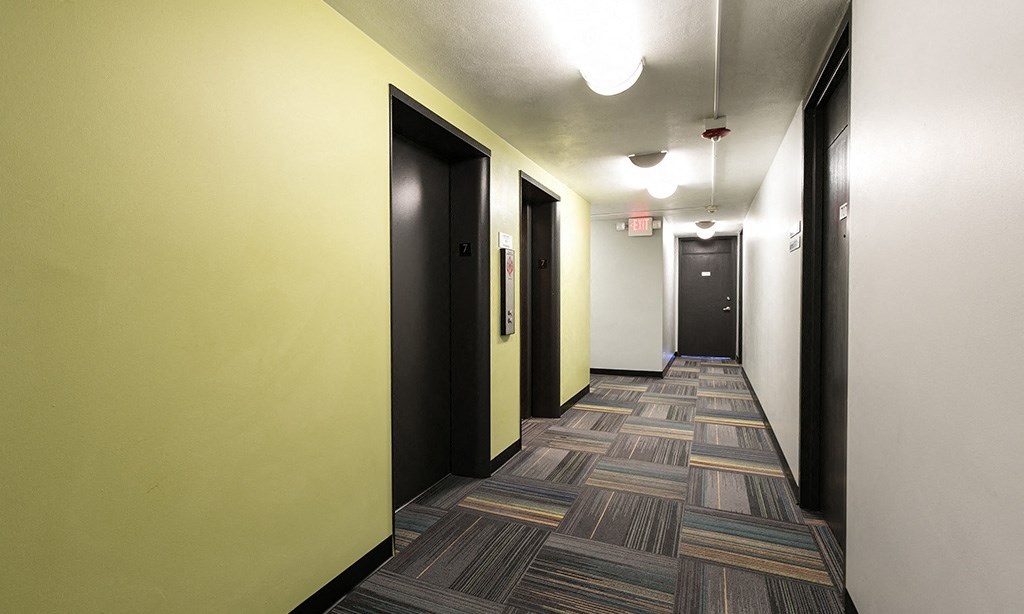 a hallway with black doors and yellow walls and a patterned flooring