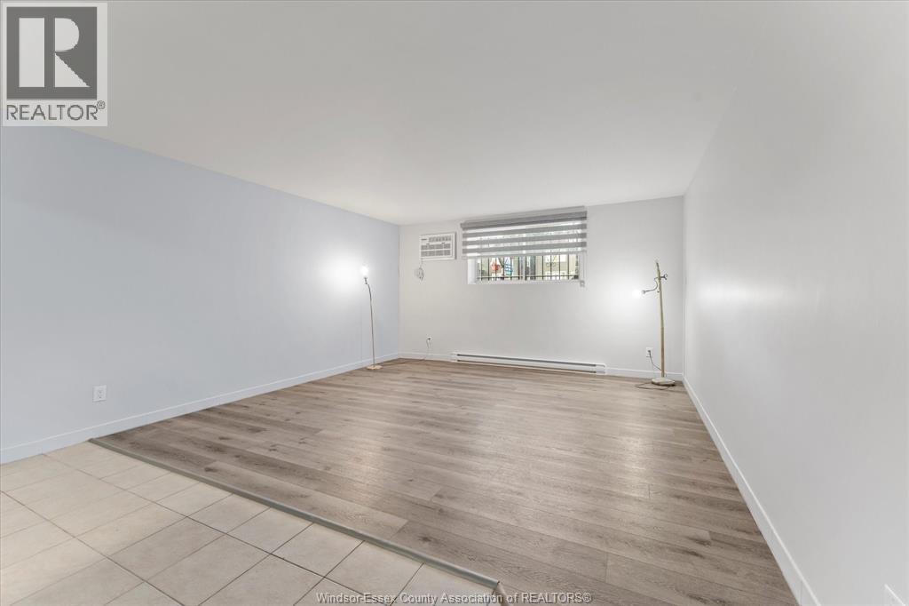 A large empty room with wooden flooring and a window with bars on it.