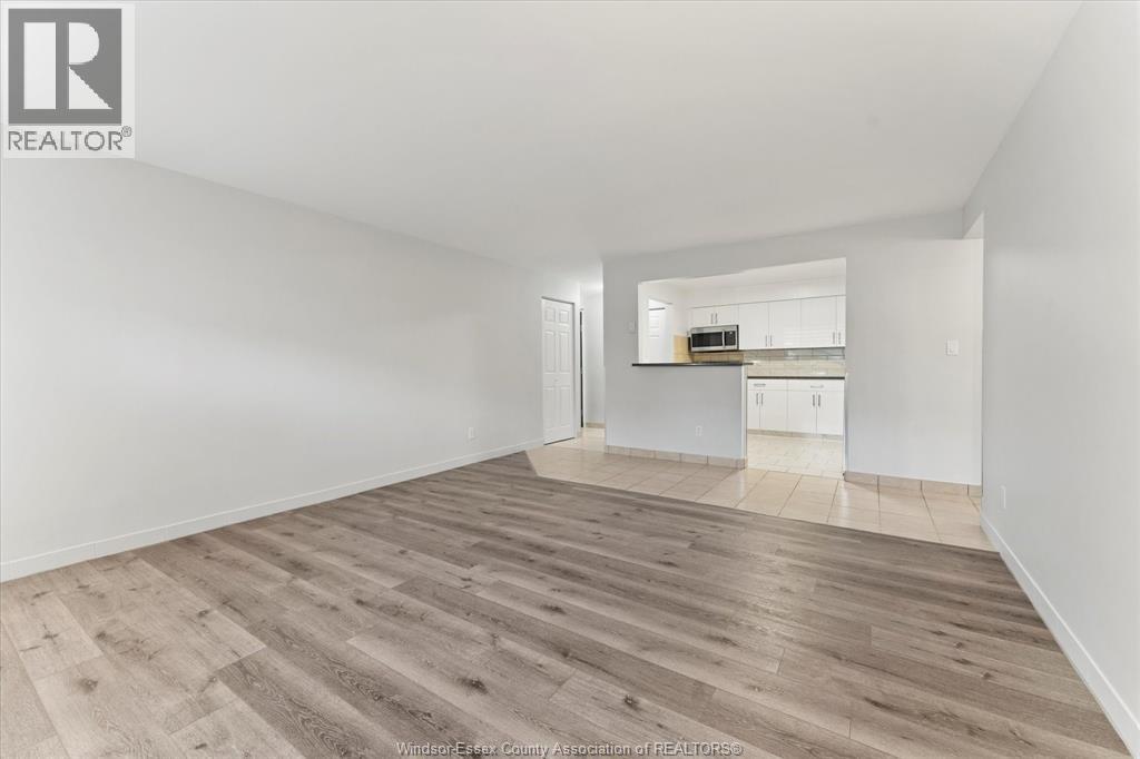 A spacious room with wooden flooring and white walls.