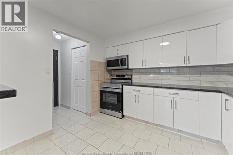 A kitchen with white cabinets and a black oven.