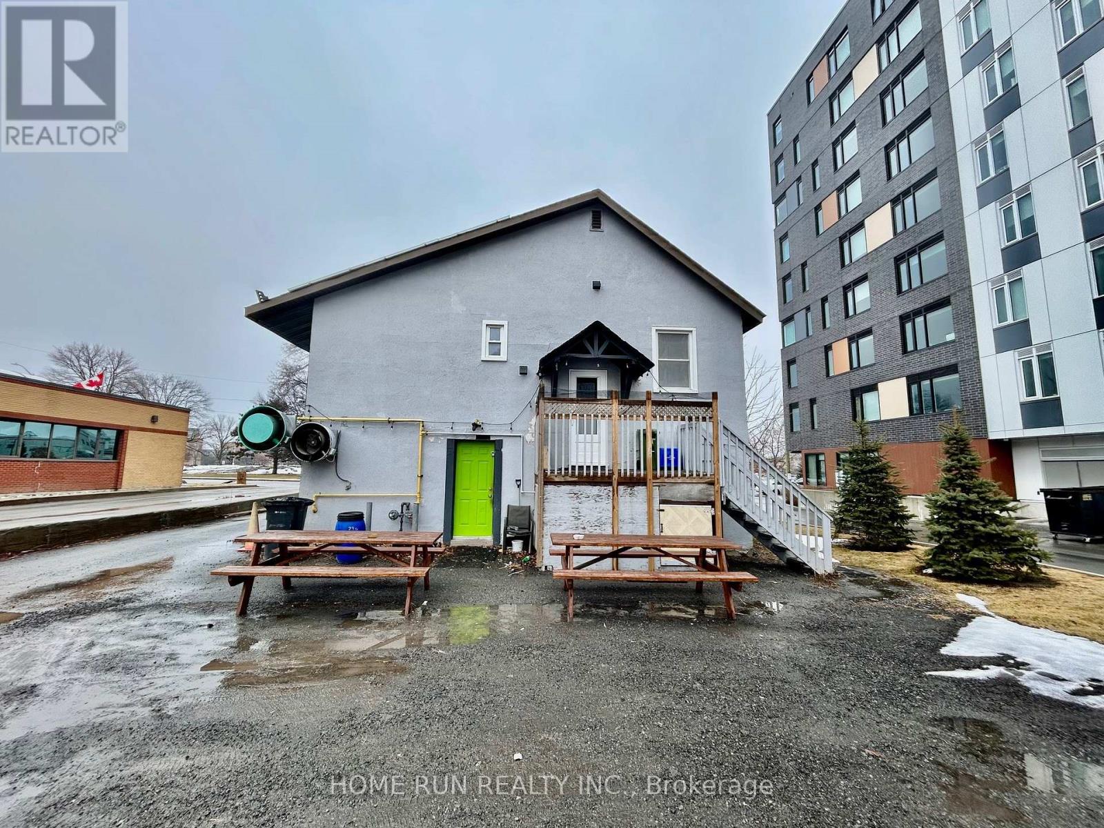 A grey house with a green door and a wooden deck in front.