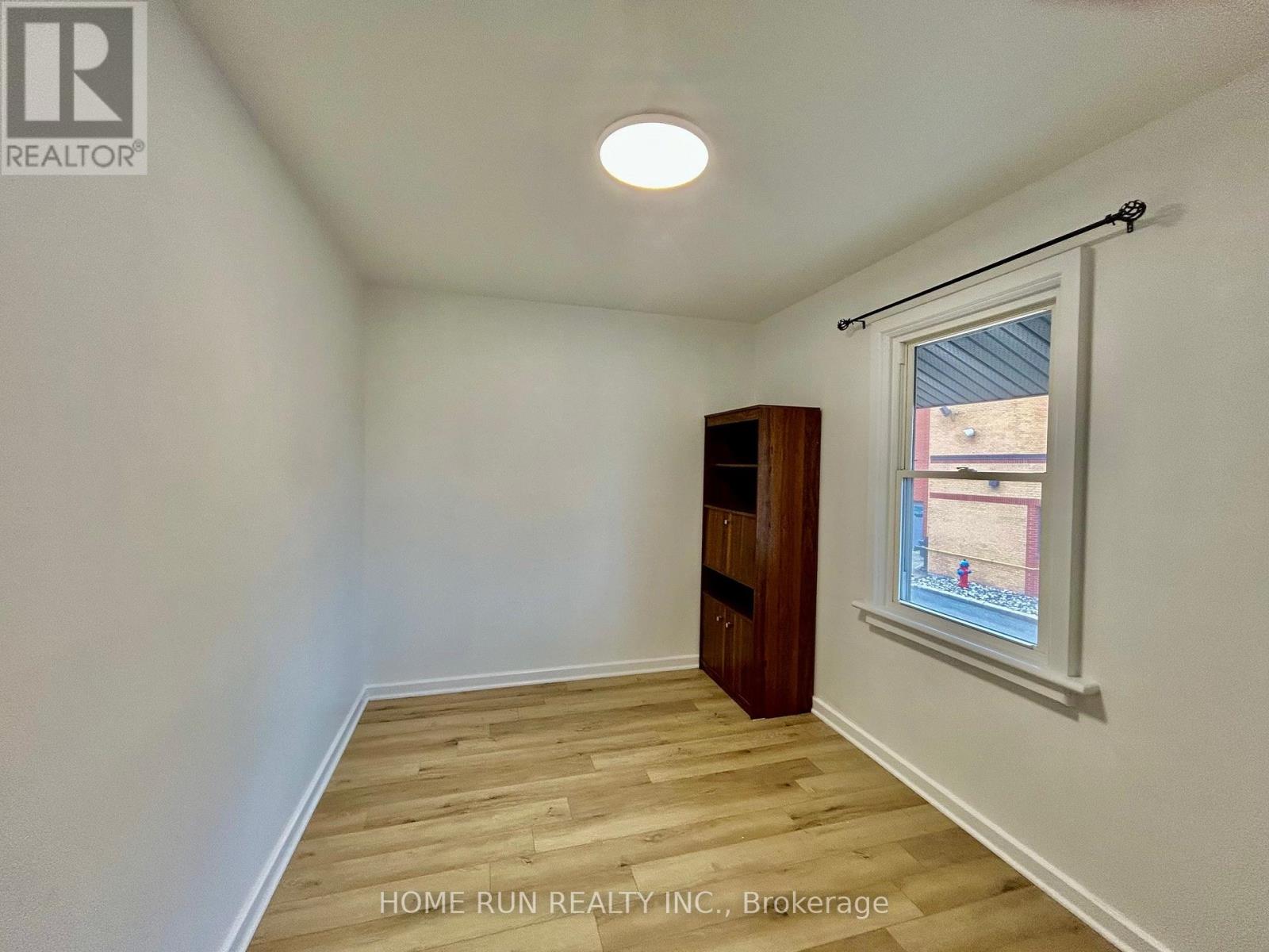 A room with a wooden floor and a window with a view of a building outside.