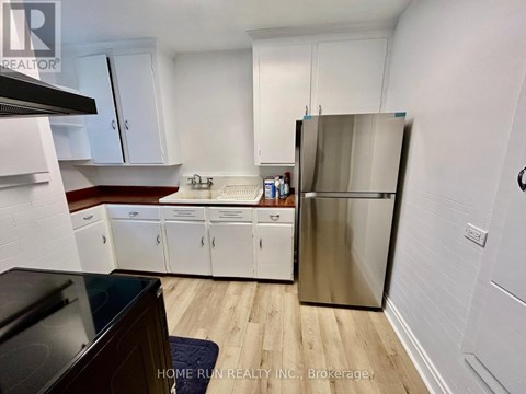 A kitchen with white cabinets and a stainless steel refrigerator.