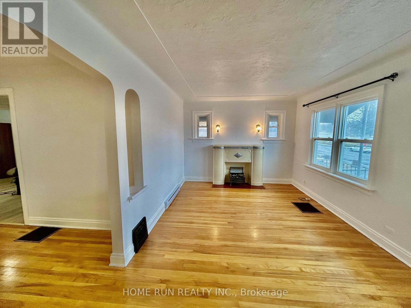 A spacious room with wooden floors and a fireplace.