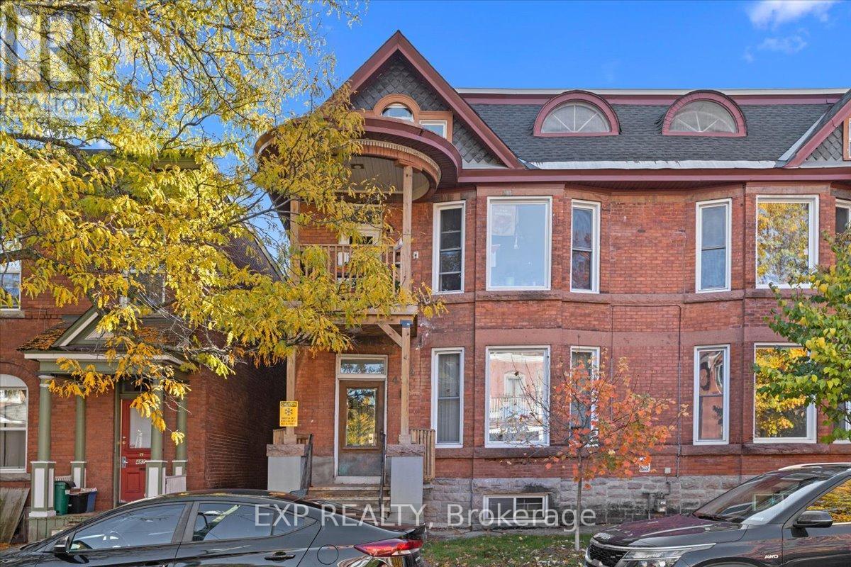 A large red brick house with a tree in front.
