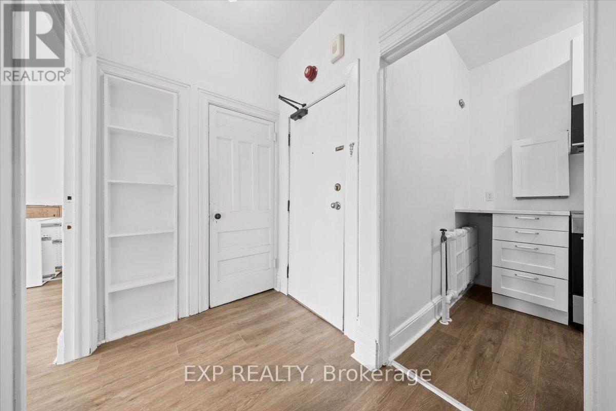 A white room with a door and a shelf.