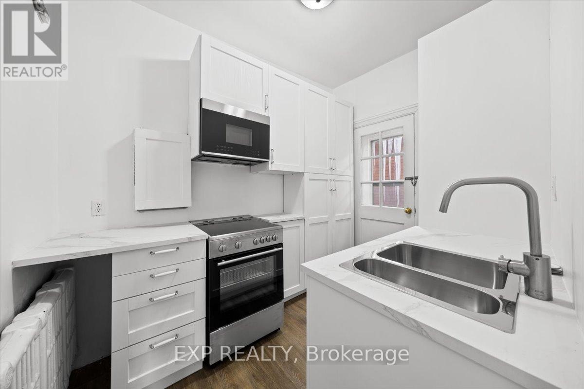 A white kitchen with a sink and a microwave.