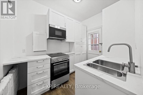 A white kitchen with a sink and a microwave.