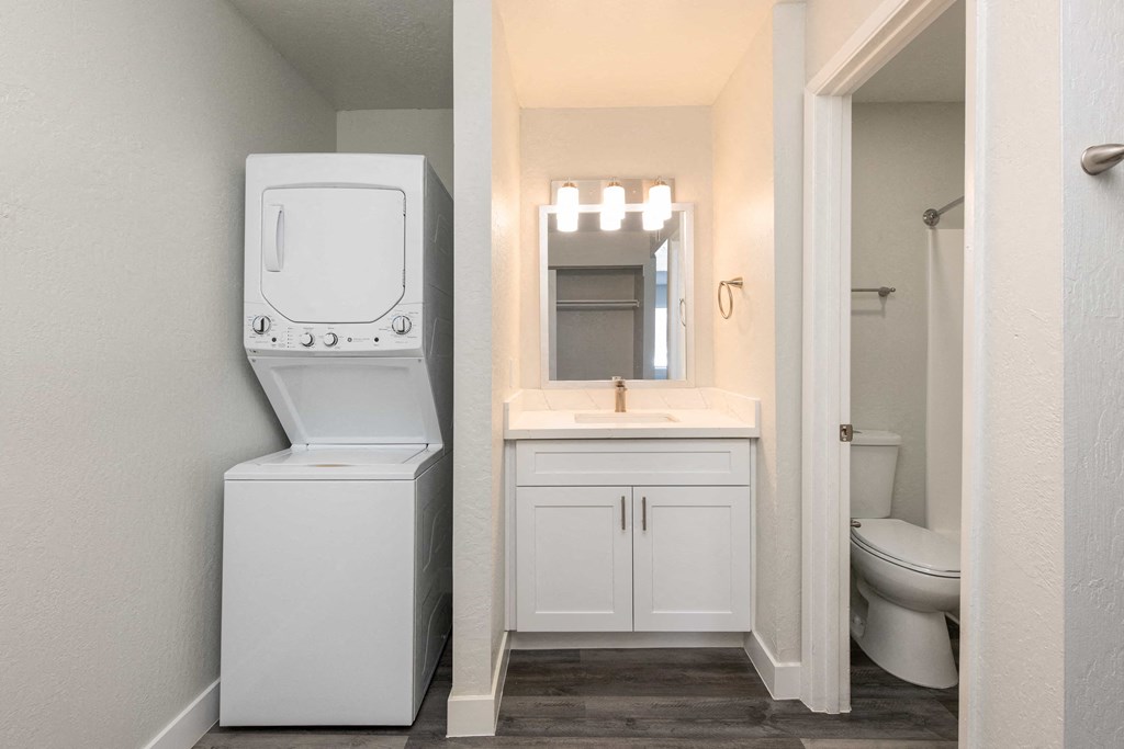 a bathroom with a washer and dryer in it and a sink and toilet