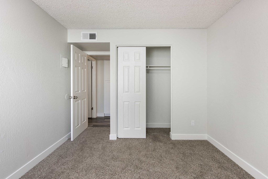 an empty bedroom with a closet and an open door
