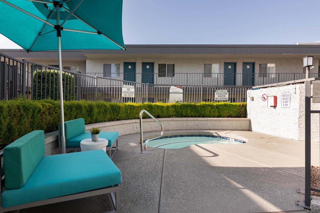 a patio with a pool and chairs and an umbrella