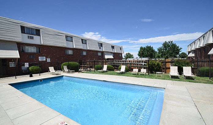 a swimming pool with chairs in front of a building