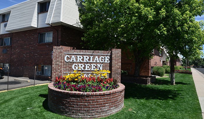a large brick sign in the grass in front of a building