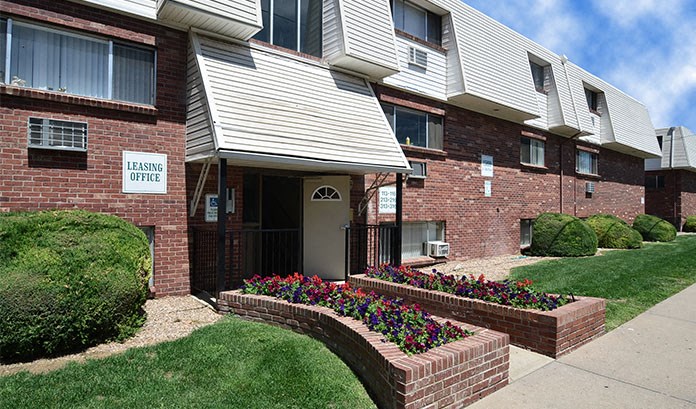 an apartment building with a sidewalk and flower beds