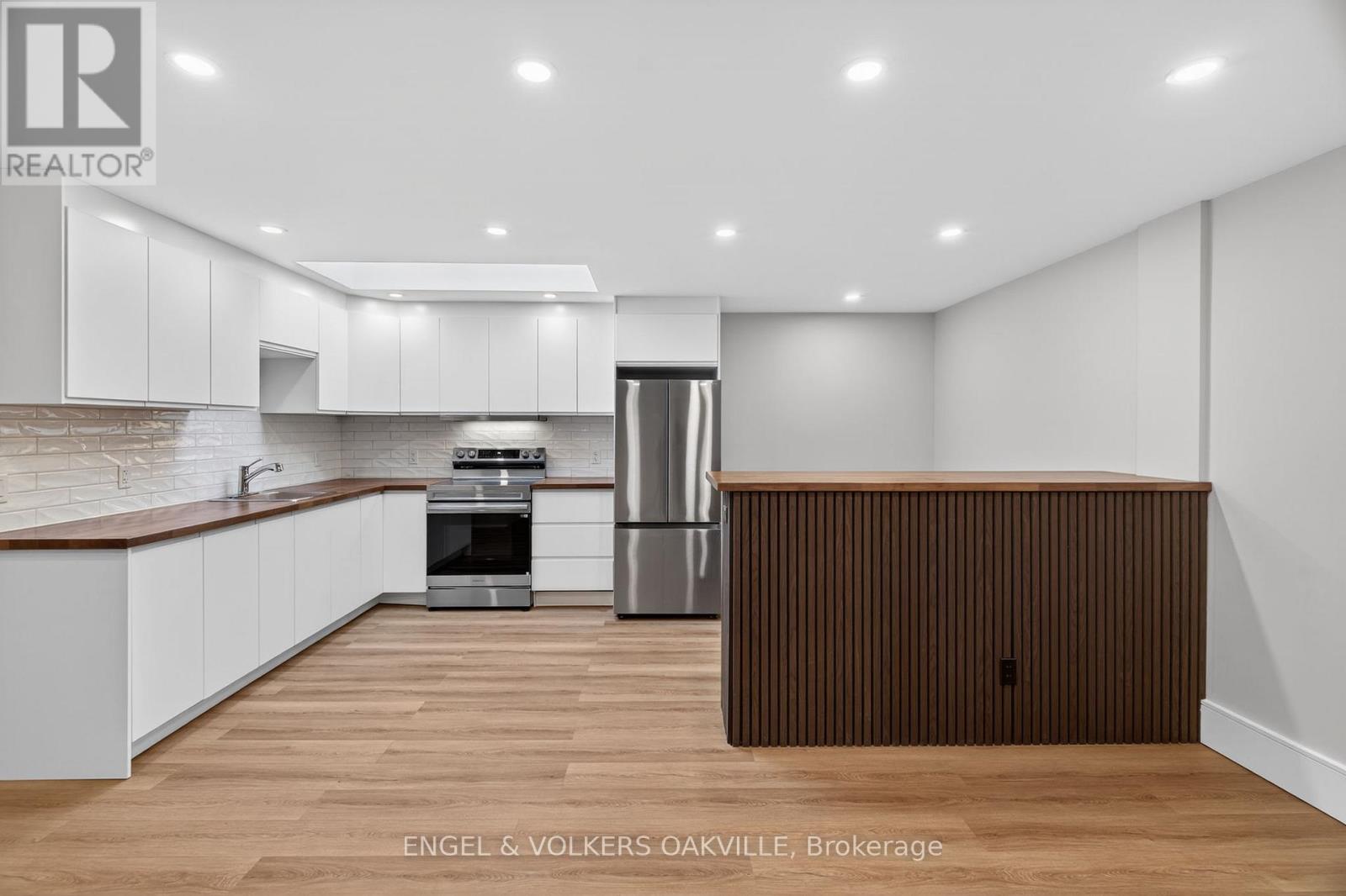 A modern kitchen with white cabinets and a wooden island.