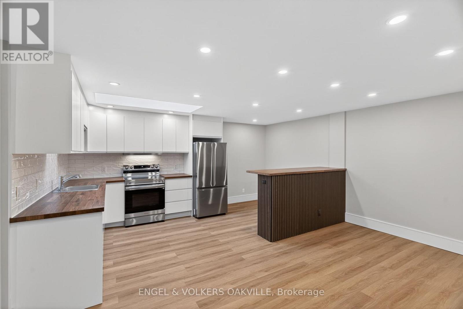 A modern kitchen with white cabinets and a wooden island.