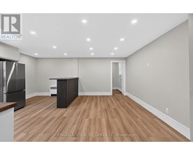 A spacious room with wooden flooring and a refrigerator.