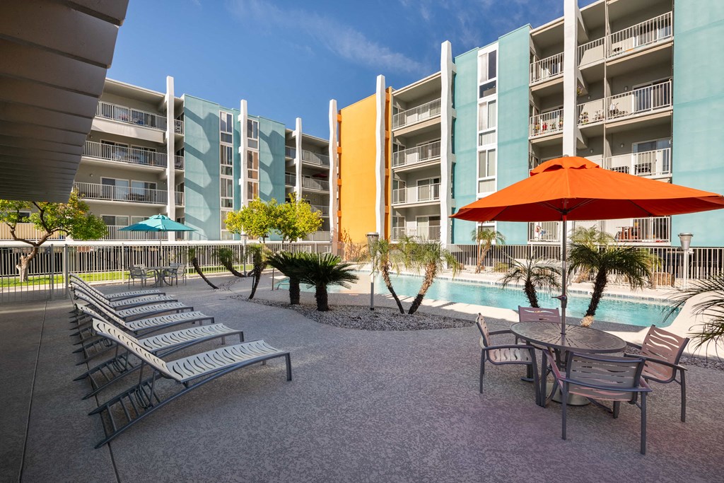 a patio with chairs and an umbrella in front of an apartment building
