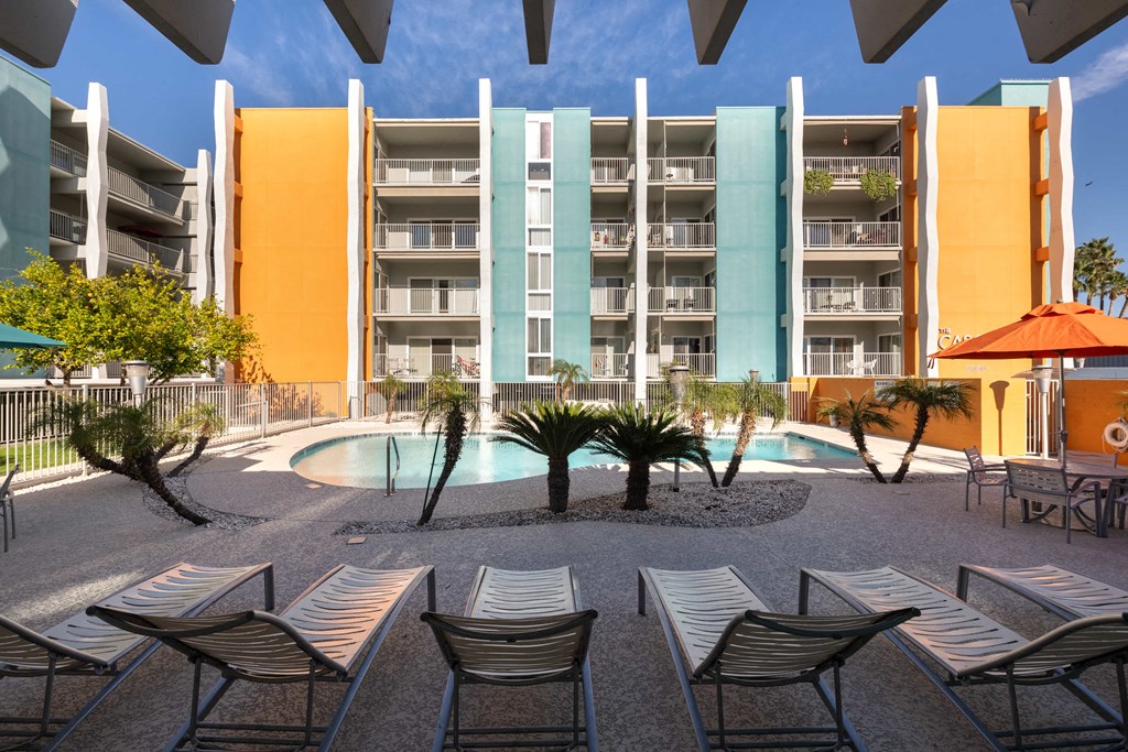 a courtyard with chairs and a pool in front of an apartment building