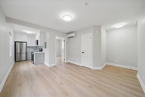 A spacious room with wooden flooring and white walls.