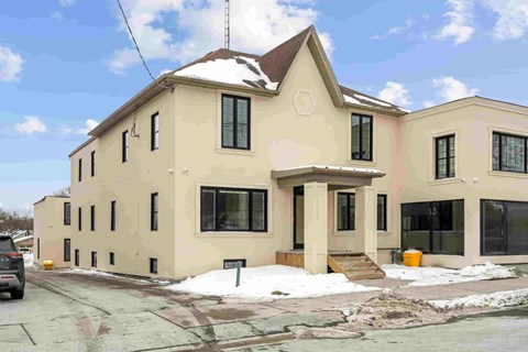 A beige house with a brown roof and a car parked in front.