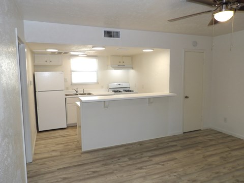 A kitchen with white appliances and wooden floors.