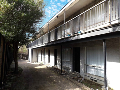 A balcony of a building with a tree on the left.