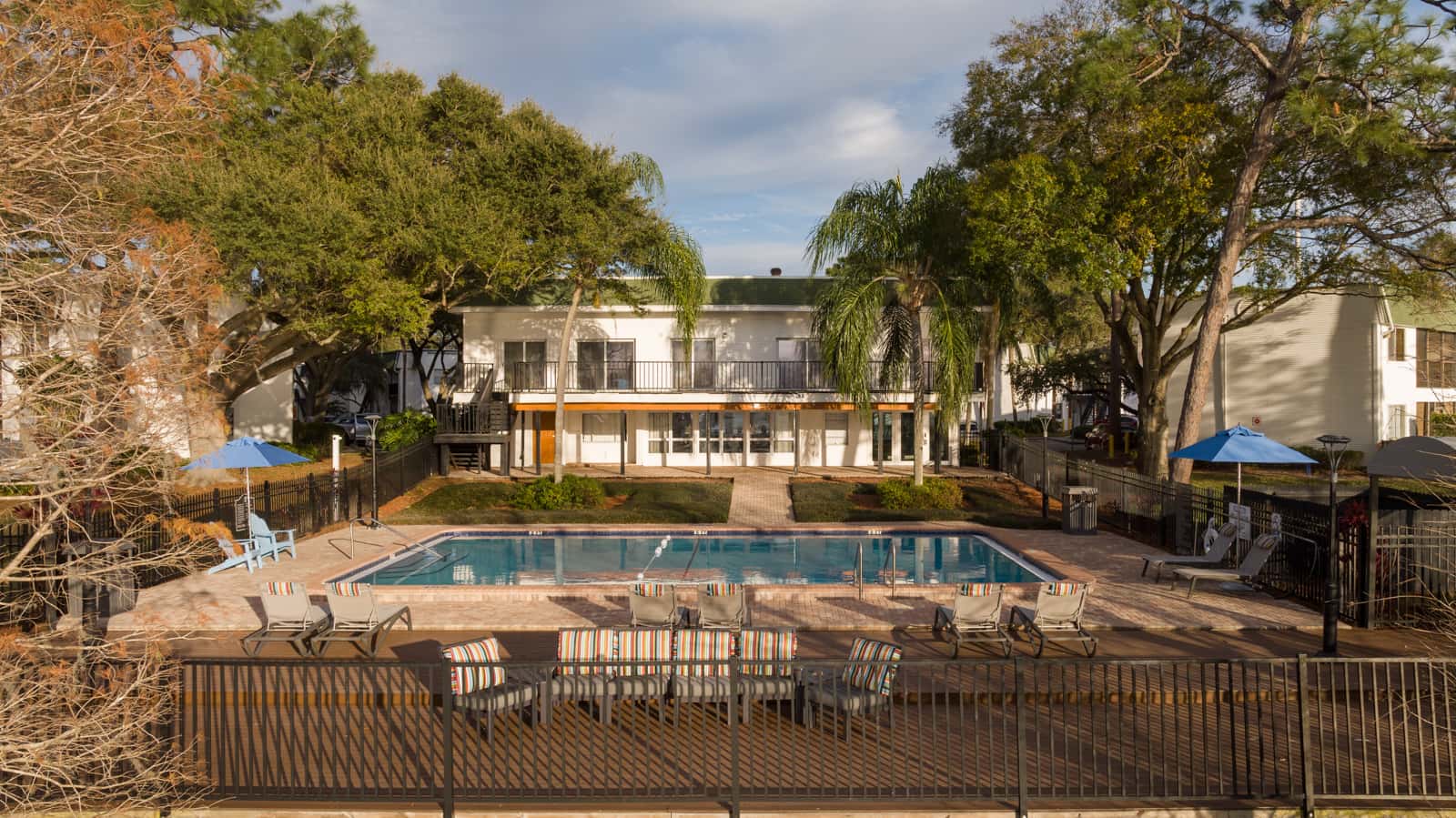 a hotel pool with chairs and a building in the background