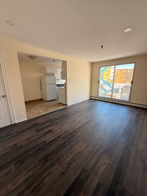 A room with wooden flooring and a window overlooking a building.
