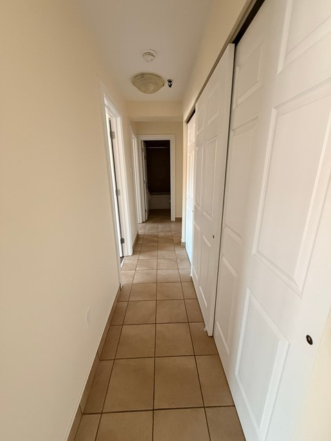 A hallway with white doors and tiled flooring.