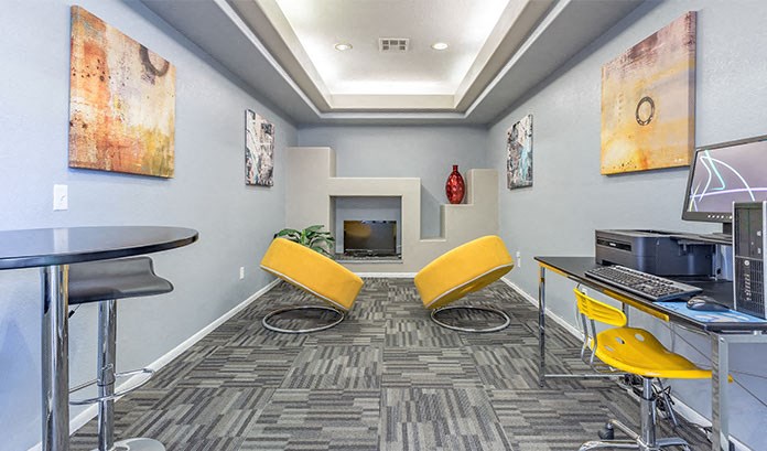 a computer room with two yellow chairs and a desk with a computer and a television