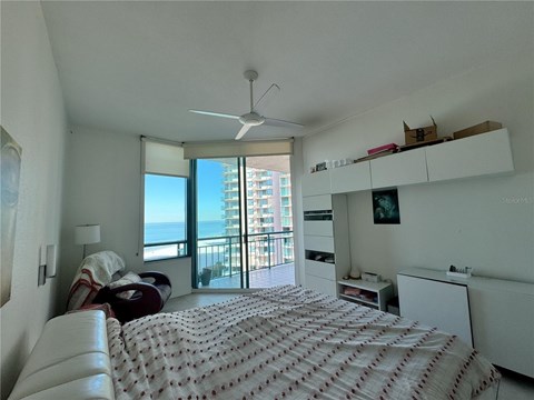 A bedroom with a large bed and a balcony overlooking the ocean.