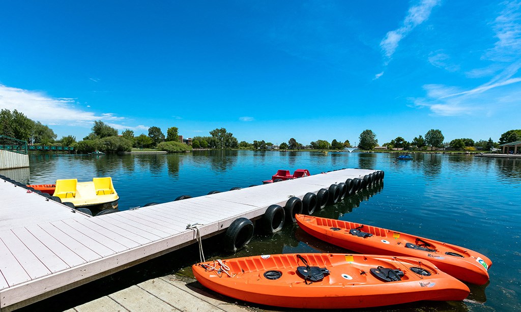 a dock with two orange kayaks and a yellow chair on the water