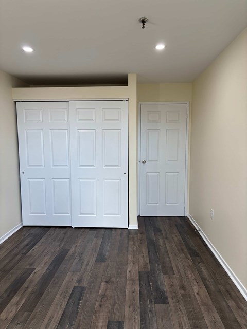 A room with a white door and a brown floor.