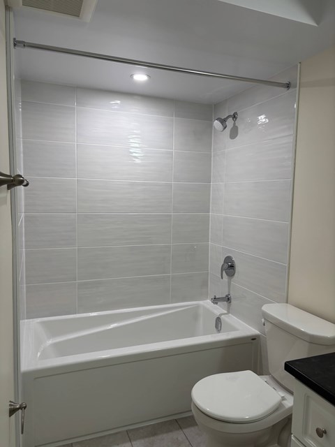 A white toilet sits next to a bathtub in a bathroom.