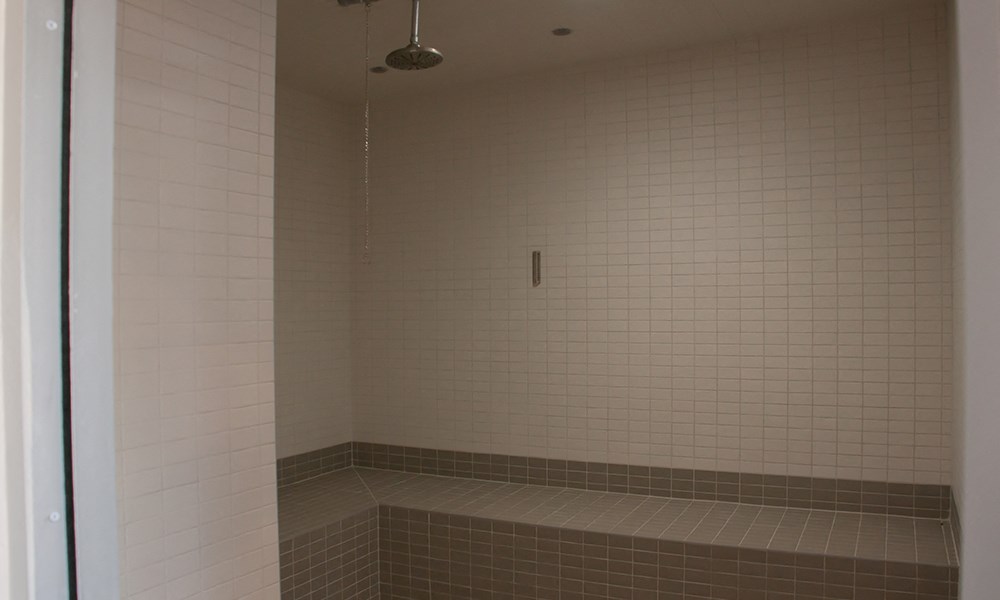 a shower in a bathroom with white tiled walls