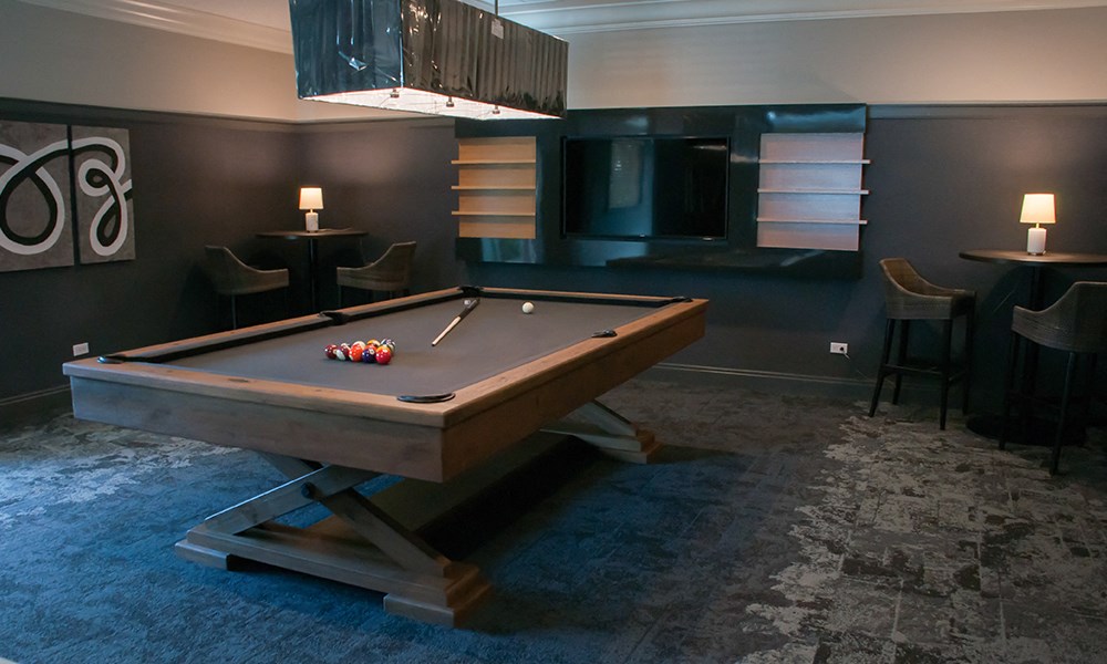 a pool table in a dark room with a chandelier