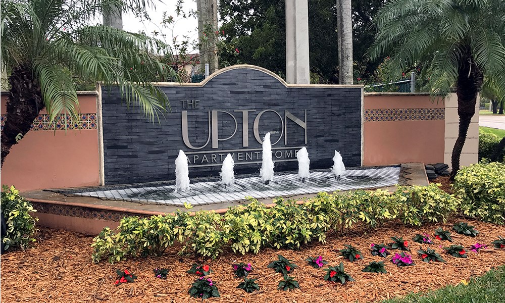a fountain in front of a sign for the uptown park and fountain