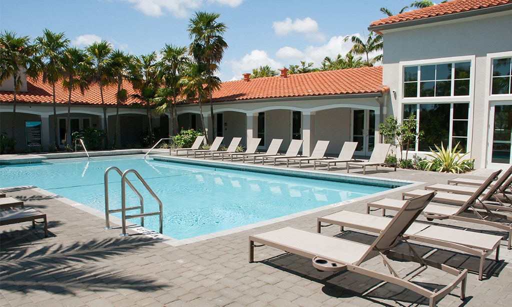 a swimming pool with lounge chairs in front of a building