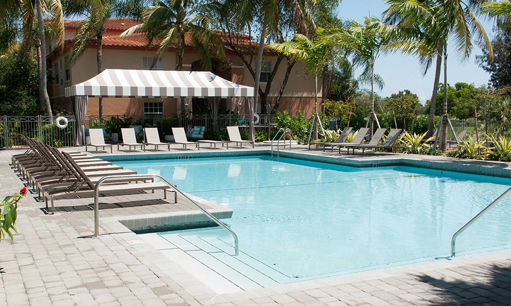 a swimming pool with chairs and a building in the background