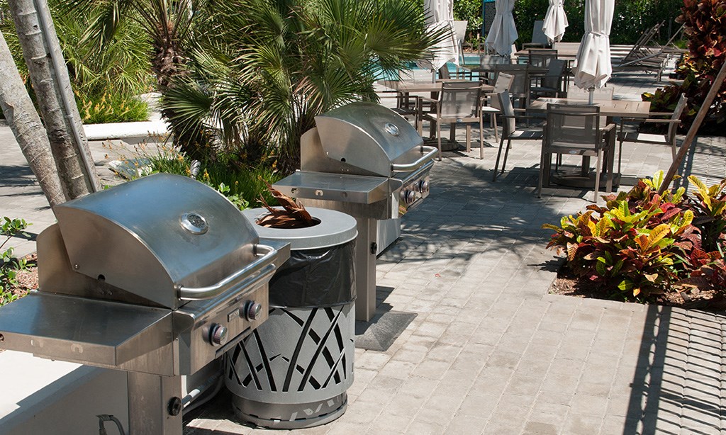 three grilling pits on a patio with tables and chairs