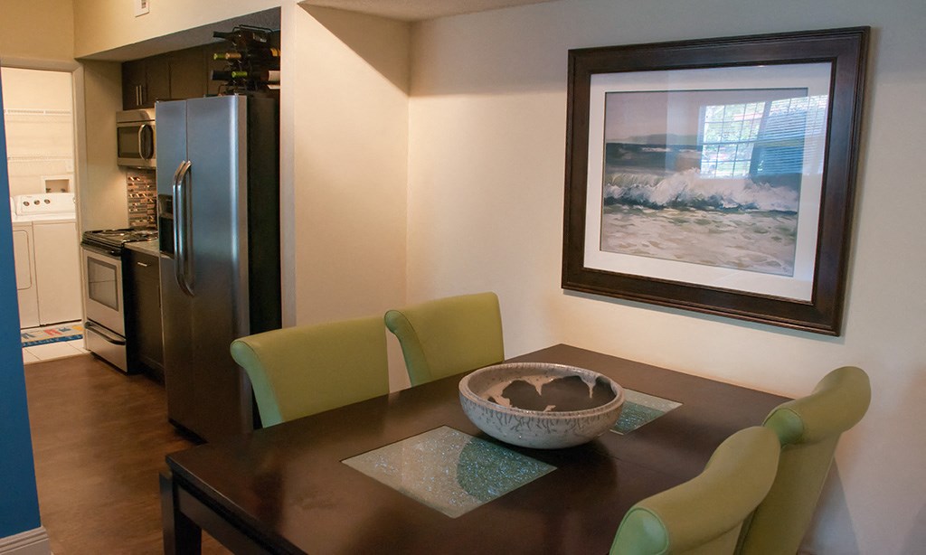 a dining room with a table and chairs and a kitchen with a refrigerator