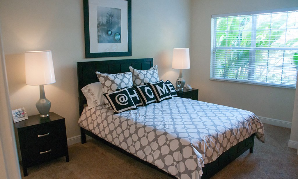 a bedroom with a bed and two lamps and a window