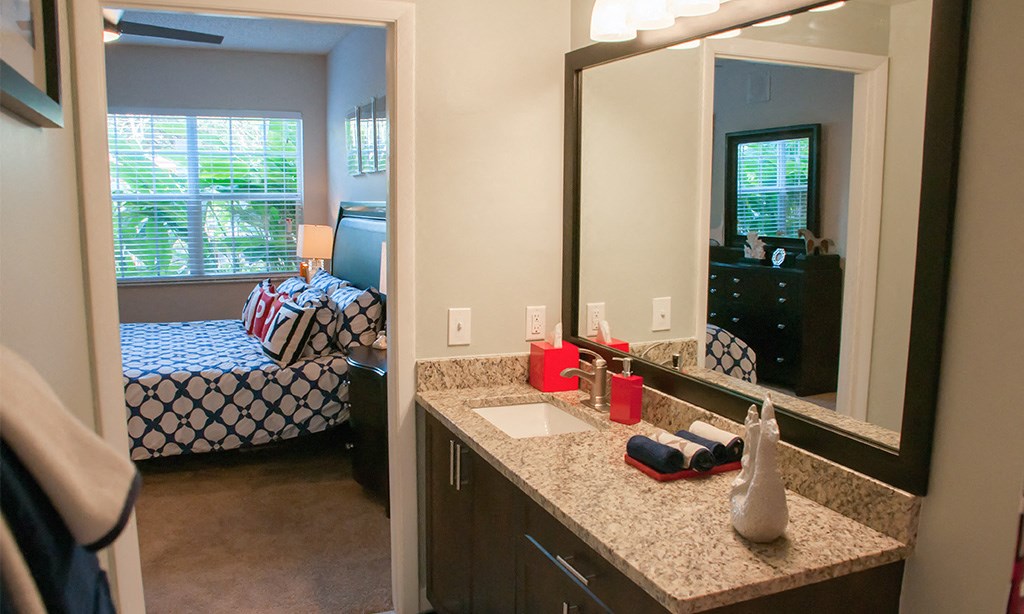 a bathroom with a mirror and a sink and a bedroom with a bed
