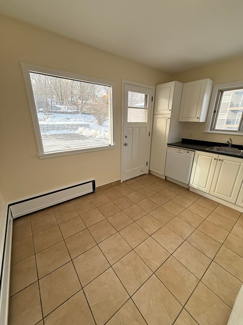 A kitchen with white cabinets and a window overlooking a snowy landscape.