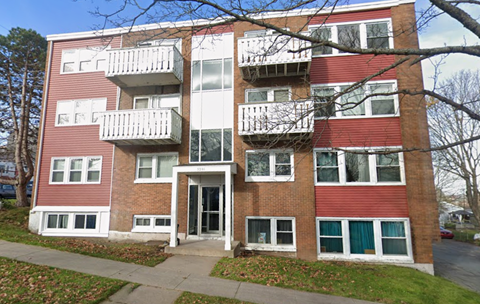 A red brick apartment building with white balconies.
