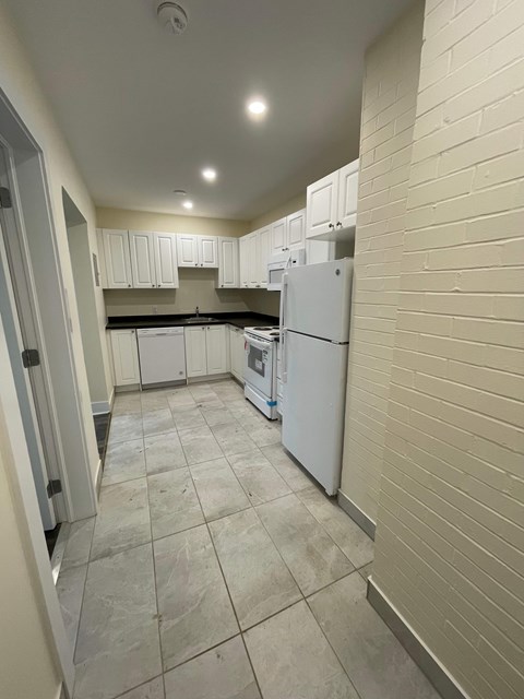 A kitchen with white cabinets and a white refrigerator.