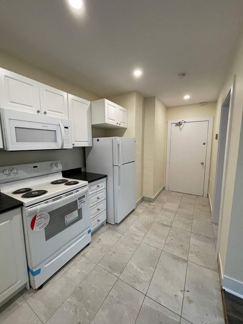 A kitchen with white appliances and cabinets.