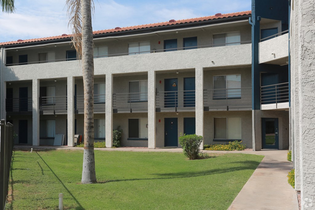 a large white building with balconies and a grass yard