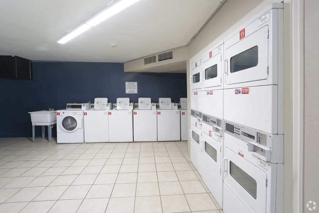 a laundry room filled with lots of white washers and dryers